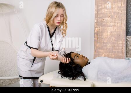 Mésothérapie, traitement des cheveux. Jolie jeune femme africaine avec des cheveux endommagés problème de recevoir le traitement en clinique. Belle jeune femme cosmetologiste Banque D'Images