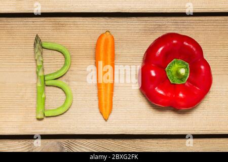 Le mot « Bio » écrit avec des légumes sur fond de bois rustique, concept - ingrédients biologiques pour la nourriture végétalienne saine et le mode de vie. Banque D'Images