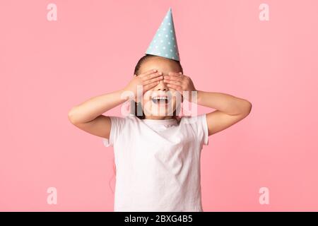 Bonne fille asiatique couvrant ses yeux, portant un chapeau de fête Banque D'Images