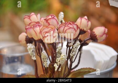 Petites roses artificielles dans un vase sur la table. Banque D'Images