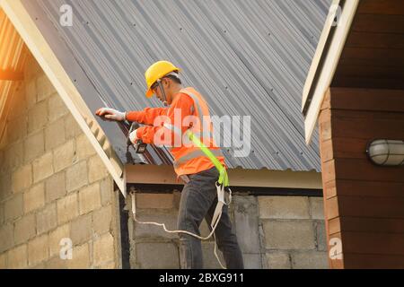 Couvreur fixant des tôles à un toit, Thaïlande Banque D'Images