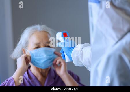 Médecin vérifiant la température d'une femme âgée à l'aide d'un thermomètre infrarouge, Thaïlande Banque D'Images