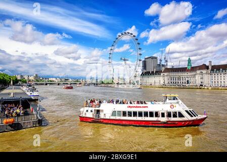 Londres, Royaume-Uni - 23 juillet 2017 : le bateau de croisière part d'un quai sur la Tamise, devant la grande roue London Eye. Les excursions sur la rivière sont un touriste populaire Banque D'Images