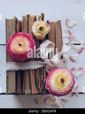 Pile de vieux livres avec fleurs sur une table en bois Banque D'Images