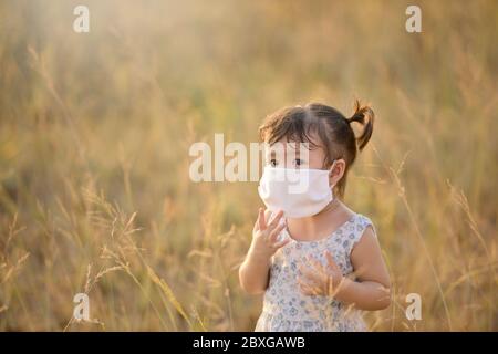Fille debout dans un champ portant un masque facial, Thaïlande Banque D'Images