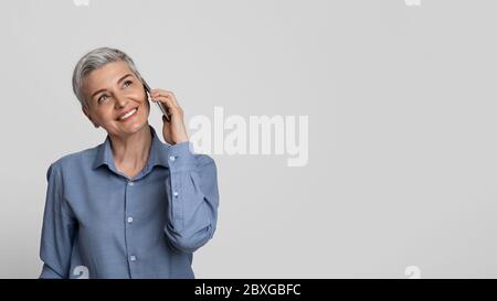 Belle femme d'affaires mature parlant sur téléphone mobile et regardant loin Banque D'Images