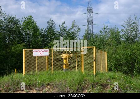 Section clôturée de l'autoroute de distribution de gaz avec un panneau avec l'inscription en russe 'gaz inflammable!' Banque D'Images