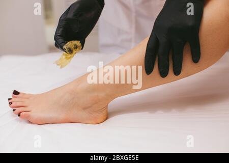 Femme ayant sa jambe cirée dans un salon de beauté Banque D'Images
