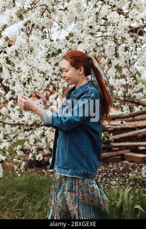 Femme souriante touchant des fleurs sur un arbre de cerisier, Russie Banque D'Images