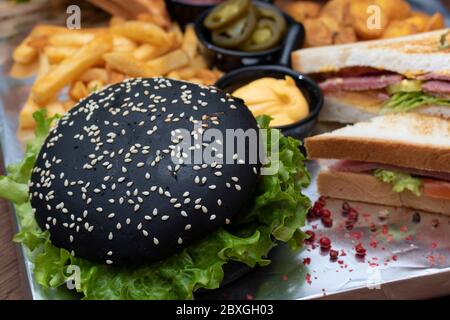 Sandwichs avec pommes de terre, frites et hamburger noir avec feuilles de salade Banque D'Images