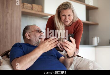 couple marié discutant d'une photo sur leur smartphone. Banque D'Images