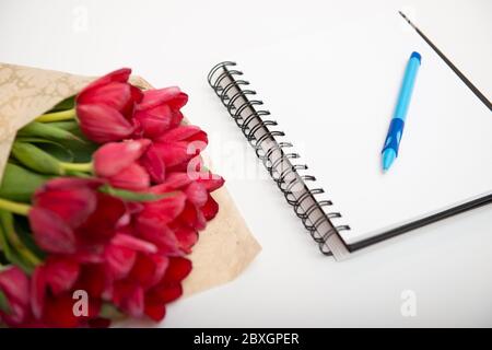 Plat de bouquet rouge tulipes isolés sur blanc avec bloc-notes et stylo avec vide pour votre texte Banque D'Images