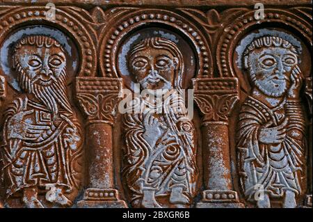 Trois personnages masculins se tiennent dans une arcade. Sculpté au début des années 1000 après JC dans un linteau de marbre blanc au-dessus d'une porte de l'église abbatiale de Saint-Génis-des Fontaines, Pyrénées-Orientales, Occitanie, France. Le linteau est la plus ancienne sculpture romane connue en France à être datée par son inscription, avec la date de sa création, 1019-1020 AD, indiquée par deux lignes d'enregistrement latin que le monastère a été fondé dans la 24ème année du règne du «roi Robert» (Robert II, qui a gouverné les Francs de 996 à 1031 AD). Banque D'Images