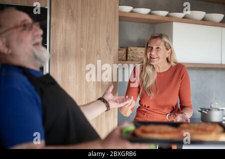 sympathique homme mature invitant pour une fête de thé dans sa cuisine. Banque D'Images