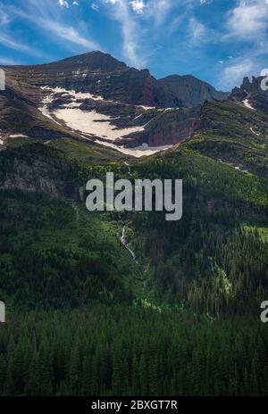 Little creek fond de neige sur la montagne au début du printemps dans le parc national des Glaciers, Montana Banque D'Images