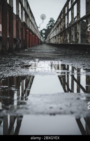 Réflexion de flaque d'eau sur un pont pédestre piétonnier Banque D'Images