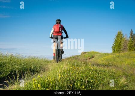 Jolie femme âgée à cheval sur son vélo électrique de montagne sur les montagnes au-dessus d'Oberstaufen, Allgau Alpes, Bavière Allemagne Banque D'Images