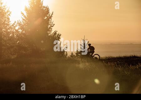 Jolie femme senior à vélo électrique de montagne dans la lumière du soleil chaude de l'aube sous le sommet de Salmas hight au-dessus d'Oberstaufen, Allgau Alpes, BAV Banque D'Images