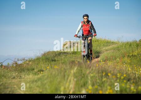 Jolie femme âgée à cheval sur son vélo électrique de montagne sur les montagnes au-dessus d'Oberstaufen, Allgau Alpes, Bavière Allemagne Banque D'Images