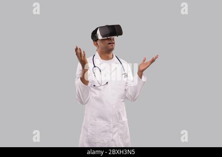 Médecin portant des lunettes VR mains sur les côtés isolé. Indian Man Doctor pointant dans la réalité virtuelle Banque D'Images