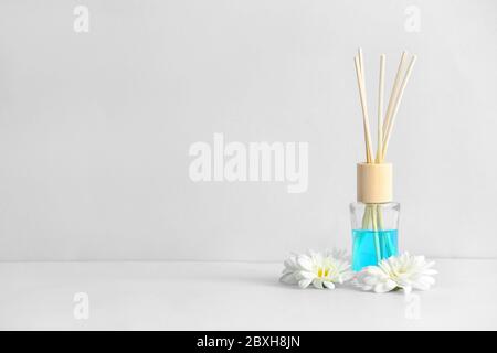 Diffuseur en roseau et fleurs sur table lumineuse Banque D'Images
