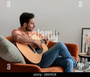 Beau jeune homme qui joue de la guitare à la maison Banque D'Images
