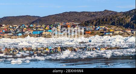 Bâtiments colorés de Ilulissat s'asseoir sur le bord de la ville de glace du port et étouffé se reflètent dans l'eau entre la glace bits. Banque D'Images