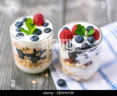Yaourt blanc dans un pot en verre avec fruits sur fond gris. Banque D'Images
