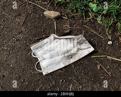 Pollution environnementale des déchets plastiques du coronavirus. Masque jetable sale sur le sol, un seul usage plastique poubelle sur l'herbe. Comment éliminer medica usagé Banque D'Images