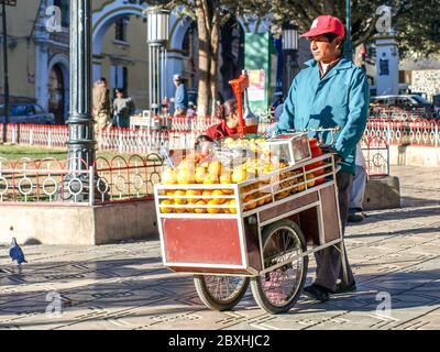 BOLIVIE, POTOSI, 4 JUILLET 2008 : vendeur de jus d'orange de rue avec petite calèche à Potosi, Bolivie, Amérique du Sud. Banque D'Images