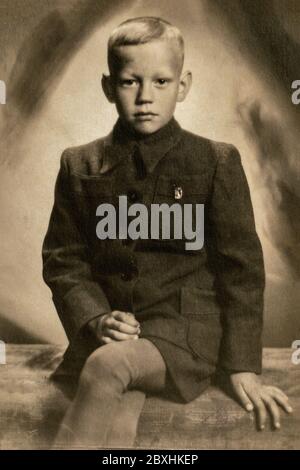 Allemagne - VERS les années 1930 : portrait d'un petit garçon assis en studio. Archive vintage photo Art déco Banque D'Images