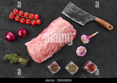 Viande de porc fraîche crue sur fond noir avec épices, vue du dessus Banque D'Images