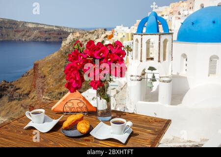 Deux tasses de café et une branche de bougainvilliers fleuris sur fond de l'architecture de l'île de Santorin Banque D'Images