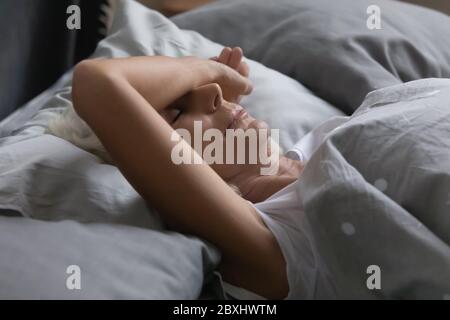 Femme mature et épuisée dormant paisiblement dans le lit de la maison Banque D'Images