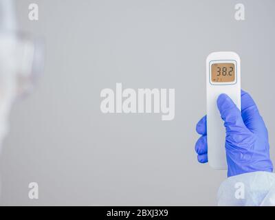 Femme tenant un thermomètre infrarouge frontal pour surveiller la température corporelle, montrant une forte fièvre, positif sur le covid19. Examen initial pour éviter le Banque D'Images