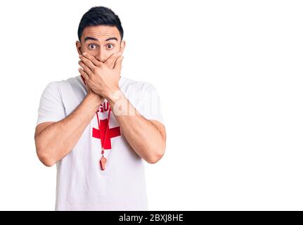 Jeune homme beau portant l'uniforme de maître-nageur choqué couvrant la bouche avec les mains pour erreur. Concept secret. Banque D'Images