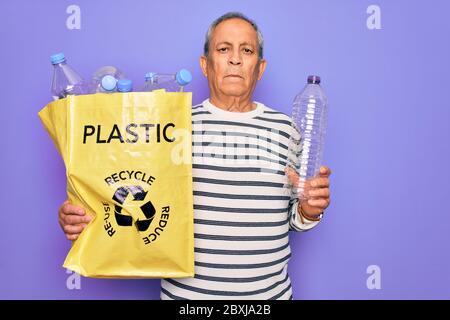 Sac de rangement de recyclage senior avec bouteilles en plastique pour recycler sur fond violet avec une expression confiante sur le visage intelligent pensant sérieux Banque D'Images