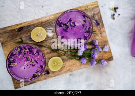 Boisson fraîche à la lavande avec citron et fleurs de lavande. Limonade froide de violette d'été, vue de dessus sur un panneau en bois. Banque D'Images