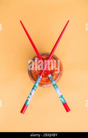 Crosse-bise rouge sur le pot Kimchi, vue de dessus sur fond jaune. Kimchi de chou fermenté probiotique. Banque D'Images