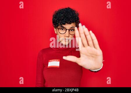 Jeune belle afro-américaine africaine femme utilisant l'autocollant avec message de présentation avec main ouverte faisant signe d'arrêt avec la sérieuse et confiante expressi Banque D'Images