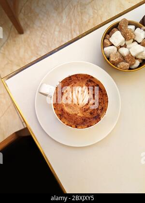 Vue Flatlay du Cappuccino avec l'art Barista et des cubes de sucre sur la table de café à Londres, Royaume-Uni Banque D'Images