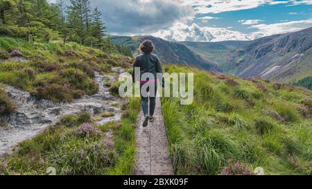 Femme marche sur le sentier au sommet de la montagne dans la vallée de Glendalough, dans les montagnes de Wicklow, en Irlande. Jour d'été. Banque D'Images