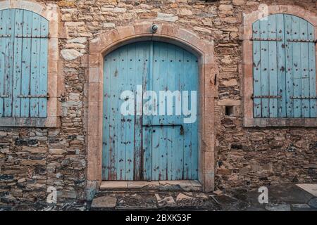 Porte en bois bleu fermée et fenêtres dans la vieille brique de pierre Chypre bâtiment extérieur. Banque D'Images