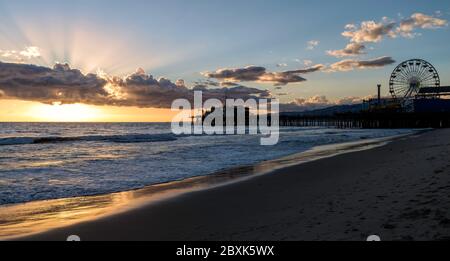 Silhouette de la jetée de Santa Monica en Californie, le soleil se couche en faisant tourner l'or de l'océan. Banque D'Images