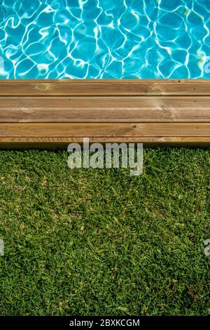 Piscine d'eau claire avec terrasse en bois et herbe verte autour Banque D'Images