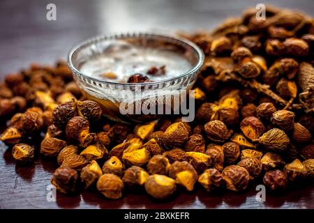 Une prise de soapnut, de reetha ou d'aréetha dans un sac de tireur avec un peu de son shampooing naturel dans un bol en verre. Banque D'Images