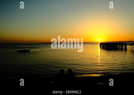 Vue sur Solent jusqu'au continent sur Totland Pier isle of Wight au coucher du soleil avec bateau à grande vitesse ancré les yachts de plage en silhouette Banque D'Images