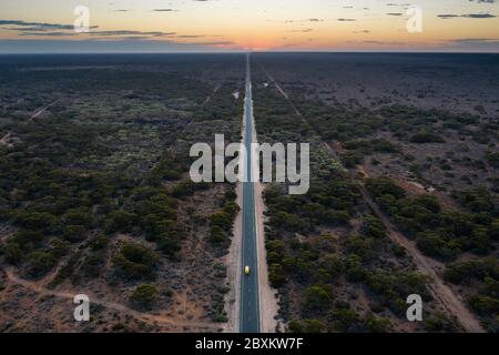 Vue aérienne au crépuscule de la longue route droite qui est l'Eyre Highway, traversant la plaine de Nullarbor en Australie méridionale Banque D'Images