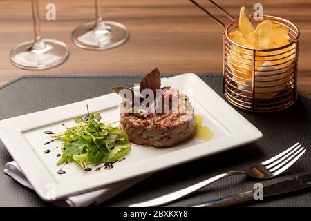 steak tartare de bœuf râpé avec épices et frites sur une table en bois Banque D'Images