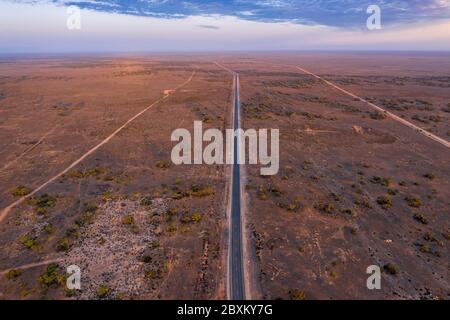 Vue aérienne à l'aube de la longue route traversant la plaine de Nullarbor en Australie occidentale Banque D'Images